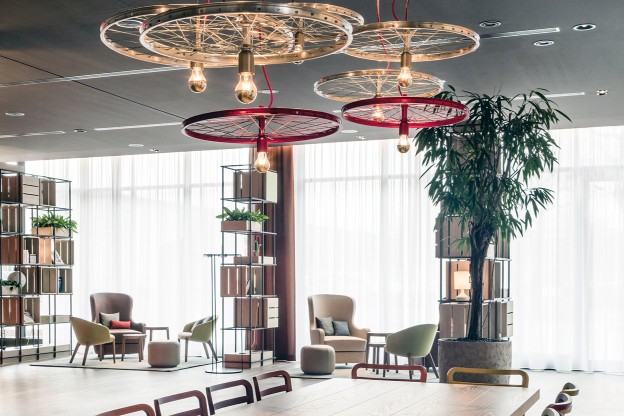A man is sitting on a table in the modern lounge area of an IntercityHotel.