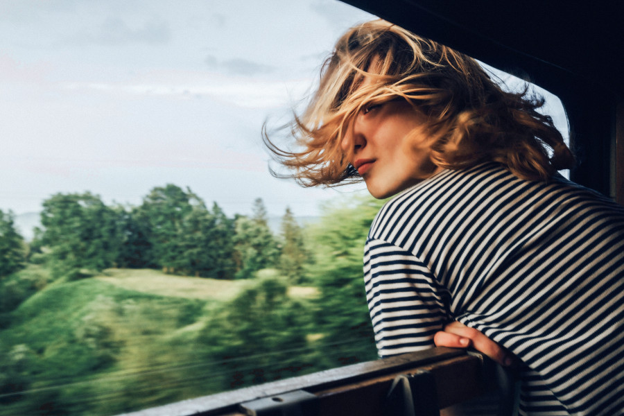 A woman is looking out of a train window.