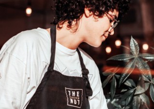 A young employee wearing a white shirt and black apron.