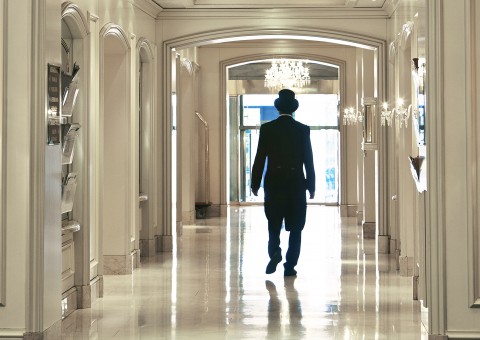 A person walking down a bright corridor in a contemporary hotel.