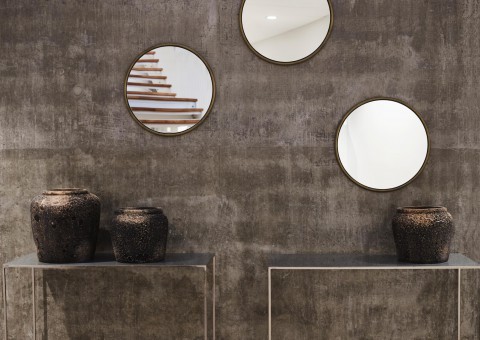 Two small, contemporary sideboards, decorated with vases and three round mirrors above them.