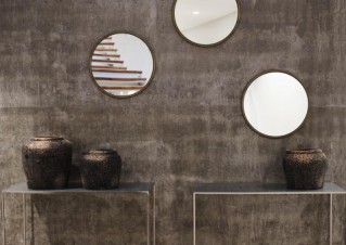 Two small, contemporary sideboards, decorated with vases and three round mirrors above them.