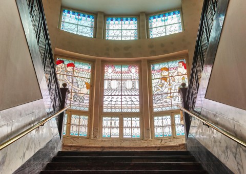 An impressive staircase. The high windows are inlaid with colourful glass.
