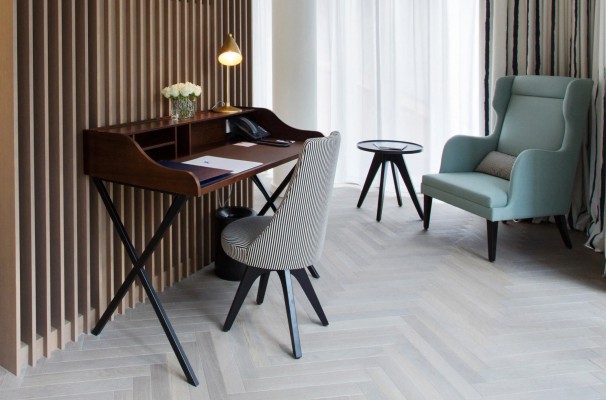 A small writing desk and a comfortable armchair in a luxurious hotel room.