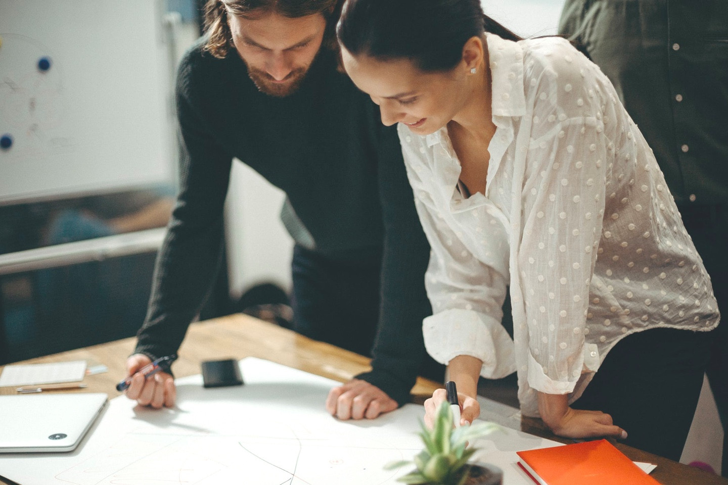 Zwei Mitarbeitende beugen sich über eine Skizze.